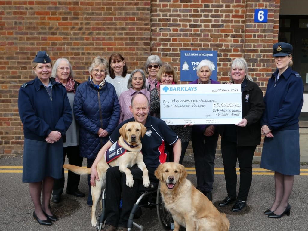 Cheque presentation photo of ladies with a man in a wheelchair and assistance dogs..