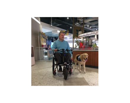 Man in an electric wheelchair with an Assistance Dog
