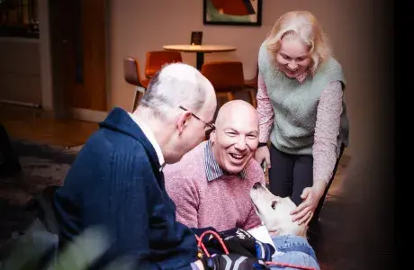 Hounds for Heroes assistance dog with partner and supporters, highlighting regular donation impact