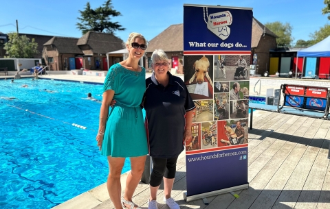2 Ladies at an outdoor pool by charity banner for Hounds for Heroes