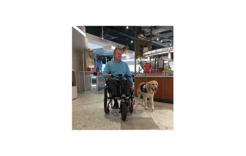 Man in an electric wheelchair with an Assistance Dog
